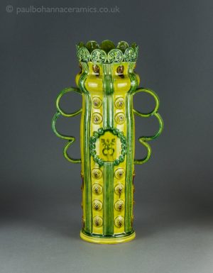 Tall 'Celebration vase' type loving cup with sprigs and birdman print. Front.